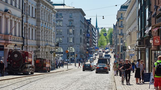 Helsingin kaupungin mukulakivikatu ja molemmilla puolilla tietä kivitalot ja keskellä kulkee raitiotie