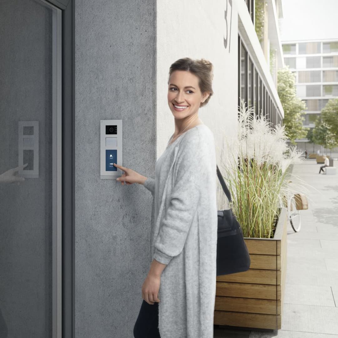 Nainen soittaa kerrostalon alaovella summeria