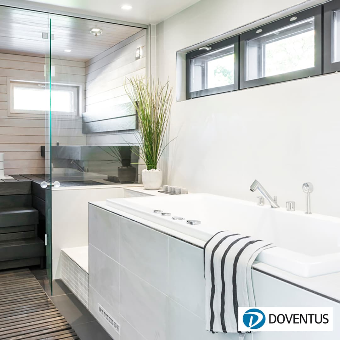 Valkoinen amme ja pesuhuone jonka taustalla lasiseinän läpi näkyy mustalauteinen saunatila